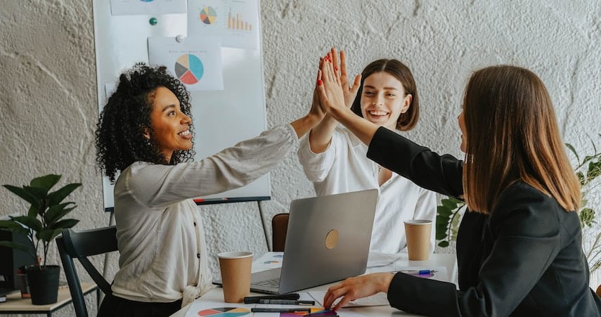 Women in B2B business high-five each other over great CRM strategy